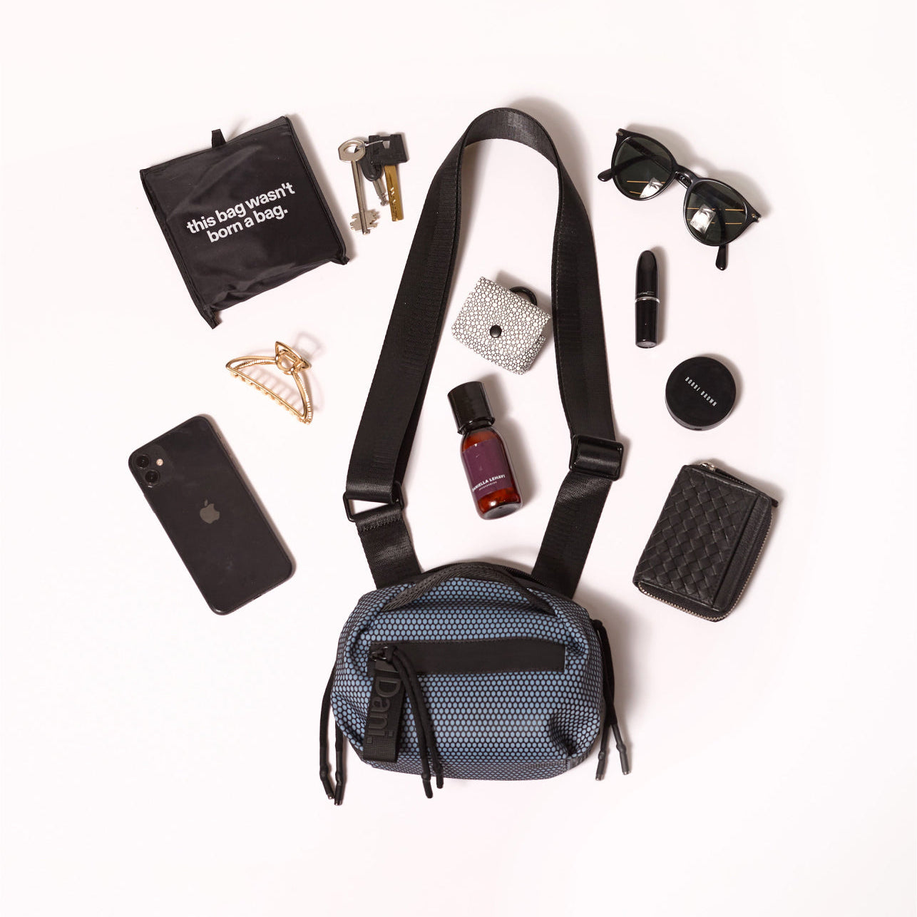 Blue crossbody bag with various items on a white background