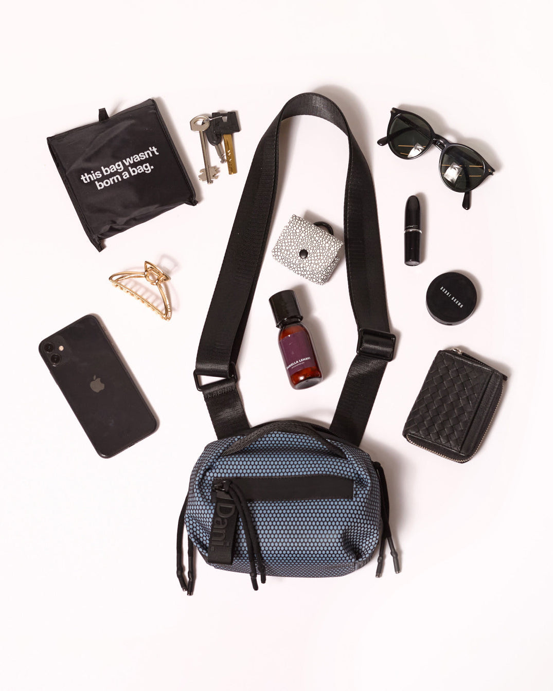 Blue crossbody bag with various items on a white background