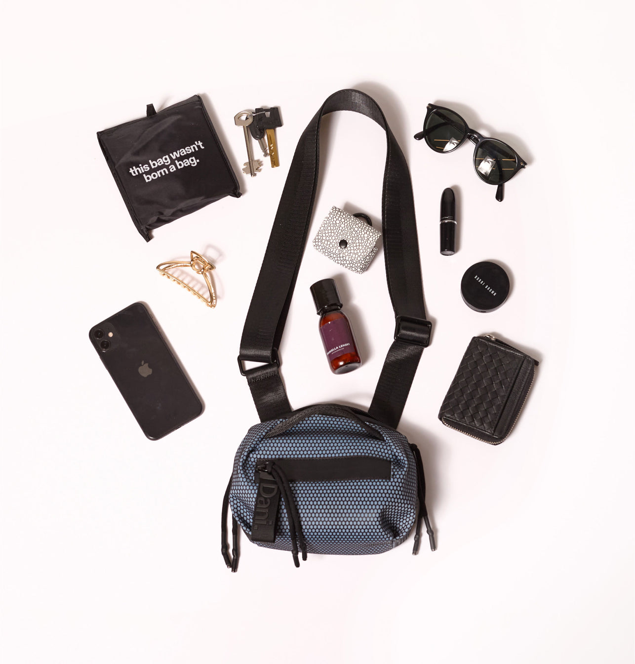 Blue crossbody bag with various items on a white background