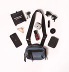 Blue crossbody bag with various items on a white background